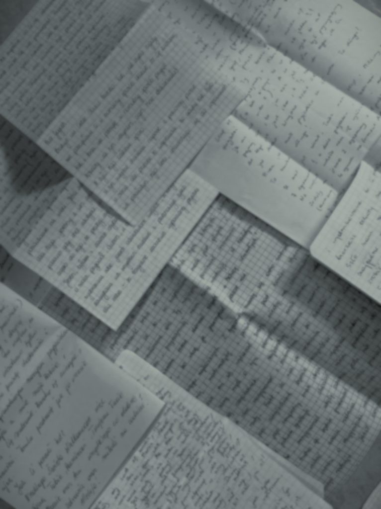 Out of focus black and white image of a collection of handwritten letters.