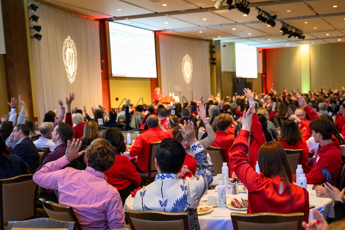 Guests raise their hands in response to the quiz questions during a lunch at the University of Wisconsin–Madison.  (Photo by Althea Dotzour / UW–Madison)